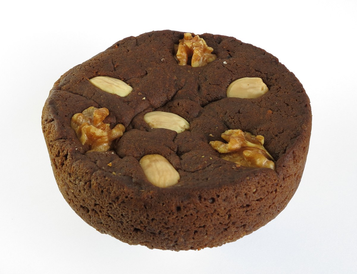 Een kleine bolo de mel uit Madeira, donkerbruin, versierd met hele amandelen en halve walnoten
