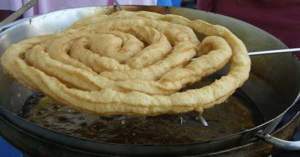 Goudbruine fartura die uit de friteuse komt op de kermis