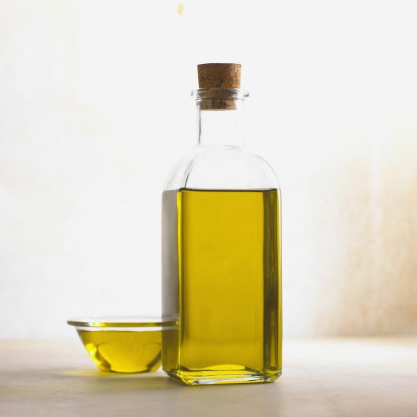Glasflasche mit Olivenöl auf hellem Hintergrund, für einen Artikel über portugiesisches Gebäck