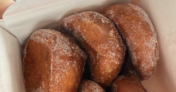 Malassadas portugaises dorées et roulées dans le sucre, dans une boîte de pâtisserie