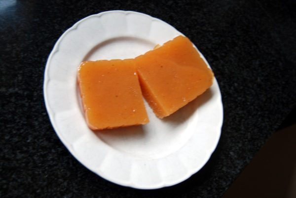 Deux tranches épaisses de pâte de coing dorée posées sur une petite assiette blanche