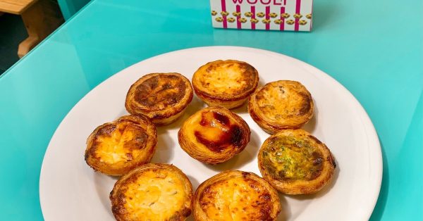 Pastéis de nata van Wooly, goudbruin en gevlekt, op een wit bord