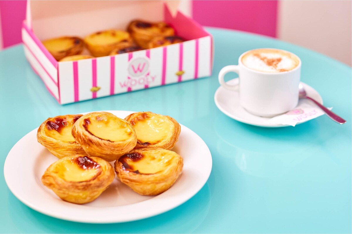 Pastéis de nata dorés et un café sur une table turquoise dans une boutique Wooly à Bruxelles