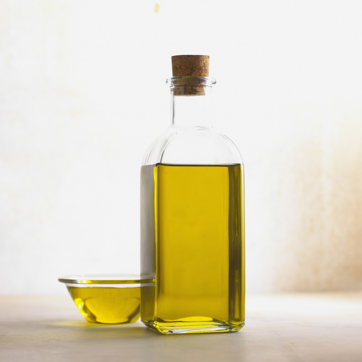 Glasflasche mit Olivenöl auf hellem Hintergrund, für einen Artikel über portugiesisches Gebäck