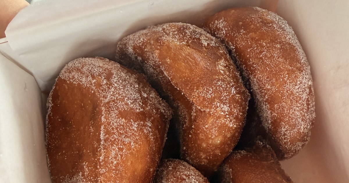Goudbruine Portugese malassadas, door de suiker gerold, in een gebaksdoos
