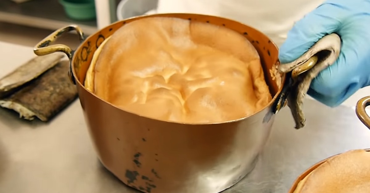 Een pão de ló uit Alfeizerão komt in zijn koperen vorm uit de oven bij een Portugese bakker