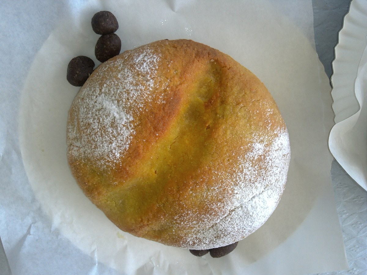 Pão de rala rond saupoudré de farine, posé sur du papier avec des olives en pâte d'amande et cacao