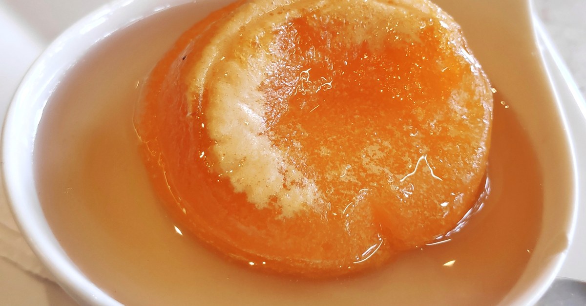 Een goudkleurige papo de anjo in heldere siroop, geserveerd in een wit schaaltje