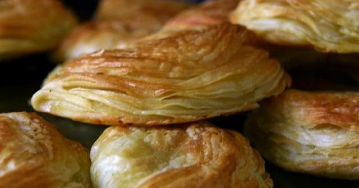 Goudbruine pastéis de Chaves op een bakplaat, bladerdeeg duidelijk zichtbaar